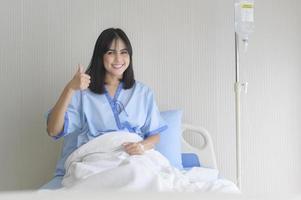 hoopvolle en gelukkige jonge geduldige vrouw in ziekenhuis, gezondheidszorg en medisch concept foto