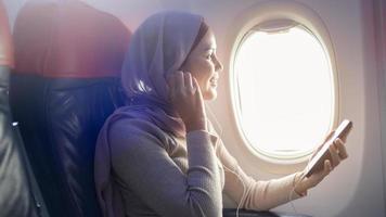 jonge moslimvrouw die hijab draagt met behulp van smartphone aan boord, reis- en vakantieconcept foto