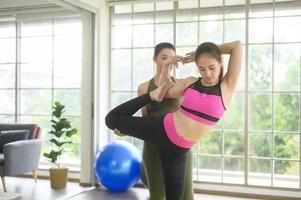 fit jonge vriend vrouwen doen yoga en meditatie thuis, sport en gezonde levensstijl concept. foto