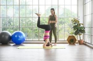 fit jonge vriend vrouwen doen yoga en meditatie thuis, sport en gezonde levensstijl concept. foto