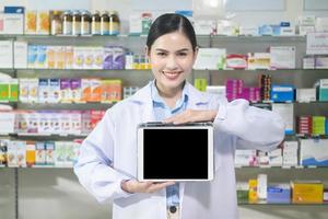 portret van vrouwelijke apotheker die tablet in een moderne apotheekdrogisterij gebruikt. foto