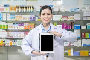 portret van vrouwelijke apotheker die tablet in een moderne apotheekdrogisterij gebruikt. foto