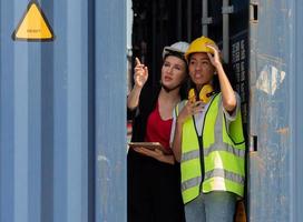 Afro-Amerikaanse vrouwelijke voorman en collega kijken naar laaddozen op containerwerf, portret. diverse ingenieursvrouwen werken op de scheepswerf, een multiculturele werkplaats. diversiteitsconcept. foto