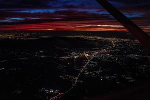 nachtzicht vanaf het vliegtuig in schemertijd met de rode lucht en het licht van de stad. foto