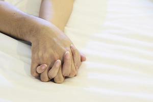 man met vrouw hand op wit bed, paar seksuele concept foto