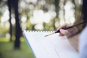 ontspannen vrouw schilderen aquarel kunstwerk in groene tuin bos natuur - mensen met creatieve kunst in de natuur stressvermindering en meditatie concept foto