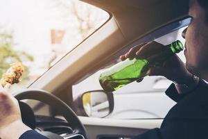 man die bier drinkt en gebraden kip eet tijdens het autorijden foto