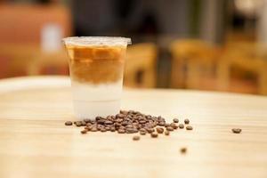 take away latte met koffieboon rond op de houten tafel foto