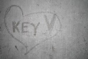 sleutelwoord in het krassen van hartteken op oude cementmuur. foto