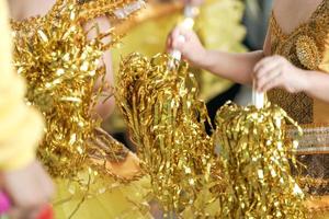 close-up kinderhand schudden glitter gouden lint om hun gele sportteam op te vrolijken. foto