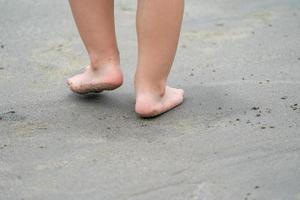 close-up kid's benen, spelen en leren op het strand. foto