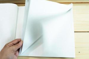 man hand open de witte lege notebook op de houten tafel. foto