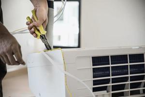 man installeert airconditioner in wooneenheid tijdens het warme seizoen in thailand foto