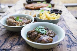 Stoofpot van rundvlees en varkensvlees met frietjes en andere recepten op houten tafel, voedselmaaltijd klaar voor eten concept foto