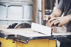 timmerman man werkt met cirkelzaagmachine tafelgereedschap voor het snijden van zijn houten stukwerk foto