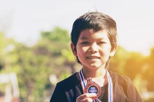 jongen krijgt bronzen medaille op zijn schoolsportdag foto