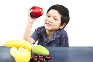 Aziatische gezonde jongen die gelukkige uitdrukking met verscheidenheids kleurrijk fruit en groente toont op witte achtergrond foto