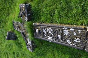 gras groeit uit de ruïnes van een gevallen kruis foto