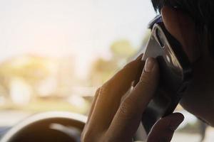 close-up van een man die gevaarlijk auto rijdt tijdens het gebruik van een mobiele telefoon foto