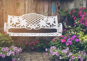 lege witte zitbank met mooie bloem over oude houten muurachtergrond foto