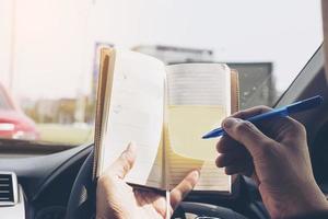 man schrijft notitieboekje tijdens het autorijden, gevaarlijk gedrag foto