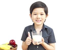 Aziatische jongen drinkt een glas melk op een witte achtergrond foto
