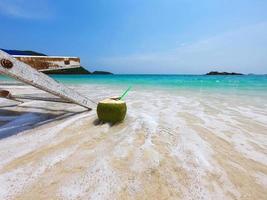 relax strandstoel met verse kokosnoot op schoon zandstrand met blauwe zee en heldere lucht - zee natuur achtergrond ontspannen concept foto