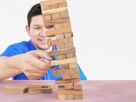 aziatische man speelt jenga, een torenspel met houten blokken om fysieke en mentale vaardigheden te oefenen foto