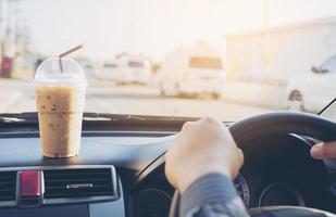 man rijdende auto met kopje koude koffie foto