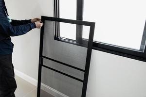 man doet aluminium frame met bril en draadscherm deur en raam installatiewerk op bouwplaats foto