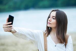 meisje buitenshuis sms'en op haar mobiele telefoon. meisje met telefoon. portret van een gelukkige vrouw sms-bericht op haar telefoon. foto