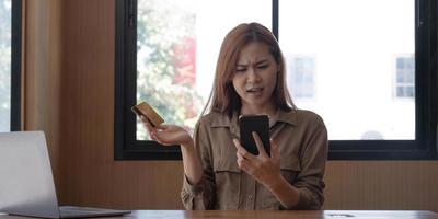 serieuze jonge aziatische vrouw die klaagt over haar creditcardproblemen met de callcenterservice van de bank. internetbankieren problemen concept foto