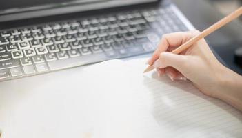 vrouwelijke hand die de laptop gebruikt terwijl ze thuis blijft vanwege de covid-epidemie, online conferentie, schrijftaken. foto