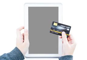 close-up van vrouwenhand die creditcard met het lege ruimtescherm van de tabletcomputer vasthoudt foto