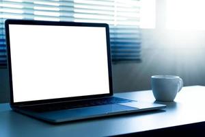 laptopcomputer met leeg scherm en een kopje koffie op tafel foto