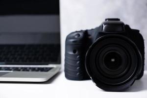 een zwarte digitale camera en een computer laptop op een tafel. foto