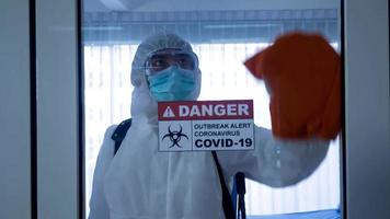 werknemer in persoonlijke beschermingsmiddelen pak schoonmaken in gebouw met spray desinfecterend water om covid 19 te verwijderen foto