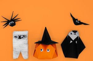 de halloween origami of papier vouwen van pompoen hoofd jack o lantern, mummie, non, spin en vleermuis op oranje achtergrond. foto
