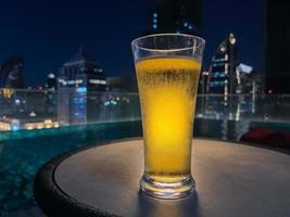 een glas bier zet op tafel in de bar op het dak met een kleurrijke stadsachtergrond. foto