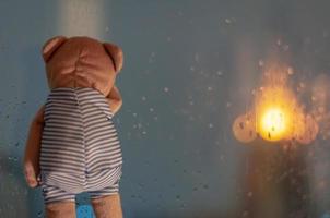 helaas teddybeer huilen bij raam in regenachtige dag. foto