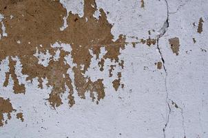 oud en gepeld van witte verf gebarsten op het bruine cementmuuroppervlak foto