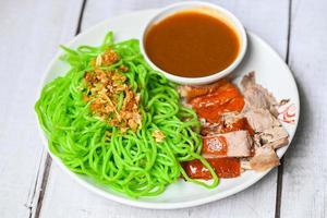 jade noodle Aziatisch thailand eten, geroosterde eend met jade noodle op witte plaat en eendensaus, groene noedels Chinees eten foto
