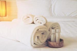 hotelhanddoek met shampoo en zeepfles op wit bed foto