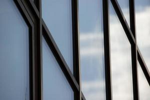 enorme moderne ramen met blauwe lucht en wolken reflectie, horizontale foto. behang, gevel van kantoorgebouw, glazen panelen. geometrie en perspectief foto