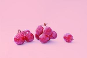grote tros rode druiven met 3 delen op roze achtergrond foto
