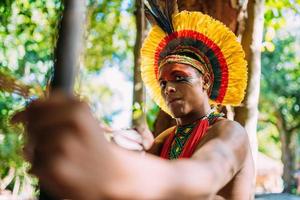 indiaan van de pataxo-stam met pijl en boog. braziliaanse indiaan met veren hoofdtooi en ketting foto