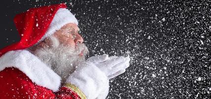 kersttradities. kerstman die sneeuwvlokken blaast. foto