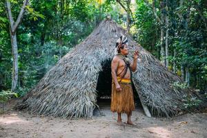 sjamaan van de pataxo-stam, gekleed in veren hoofdtooi en pijp rokend. braziliaanse indiaan die naar rechts kijkt foto