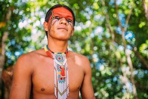 indiaan van de pataxo-stam glimlachend. braziliaanse indiaan uit zuidelijk bahia met ketting en traditionele gezichtsschilderingen naar links kijkend foto