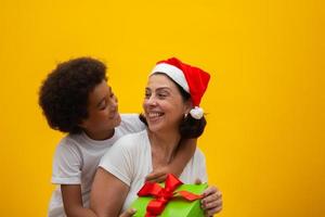 blanke moeder met zwarte zoon die geschenken uitwisselt op kerstavond. pleegkind concept. sociaal respect, huidskleur, inclusie. foto